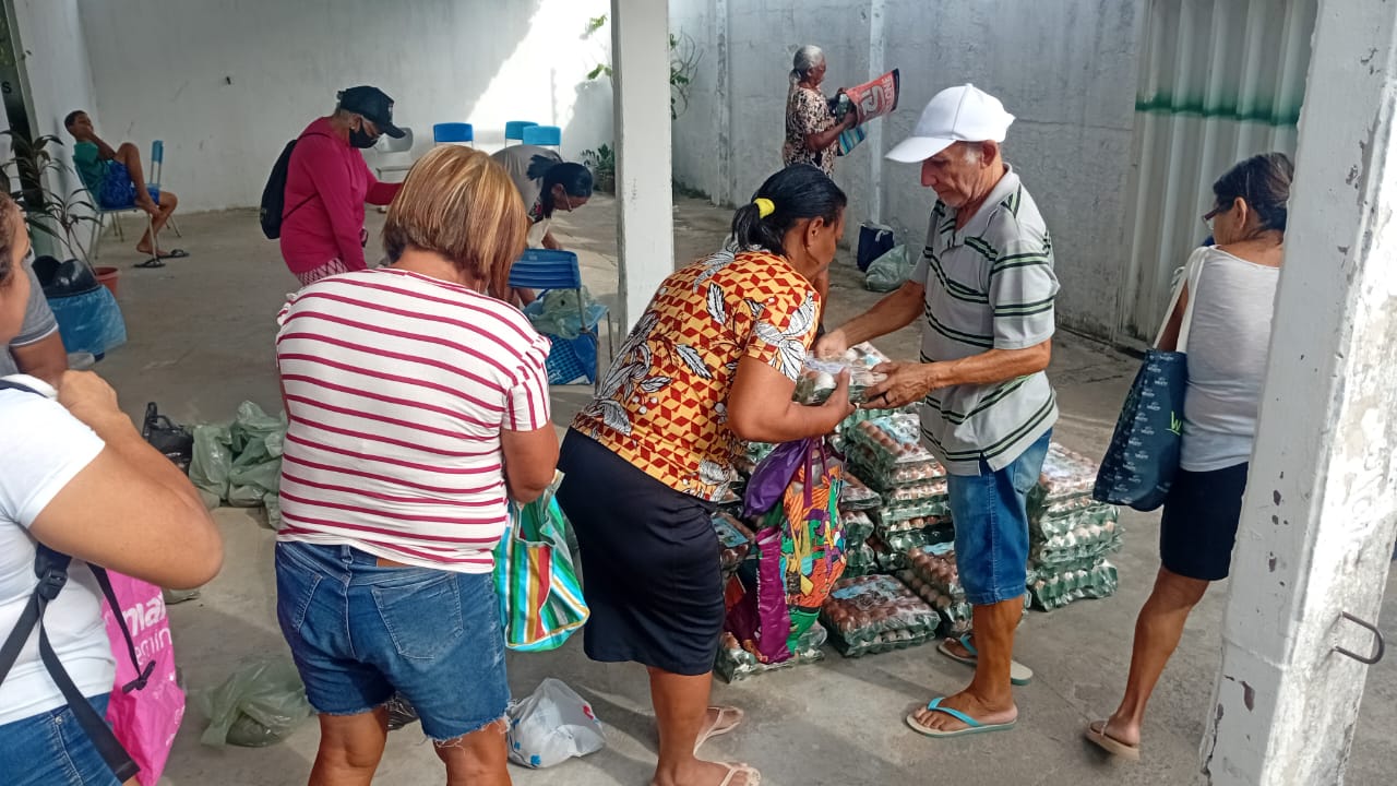 Pessoa entrega uma bandeja de ovos a participante