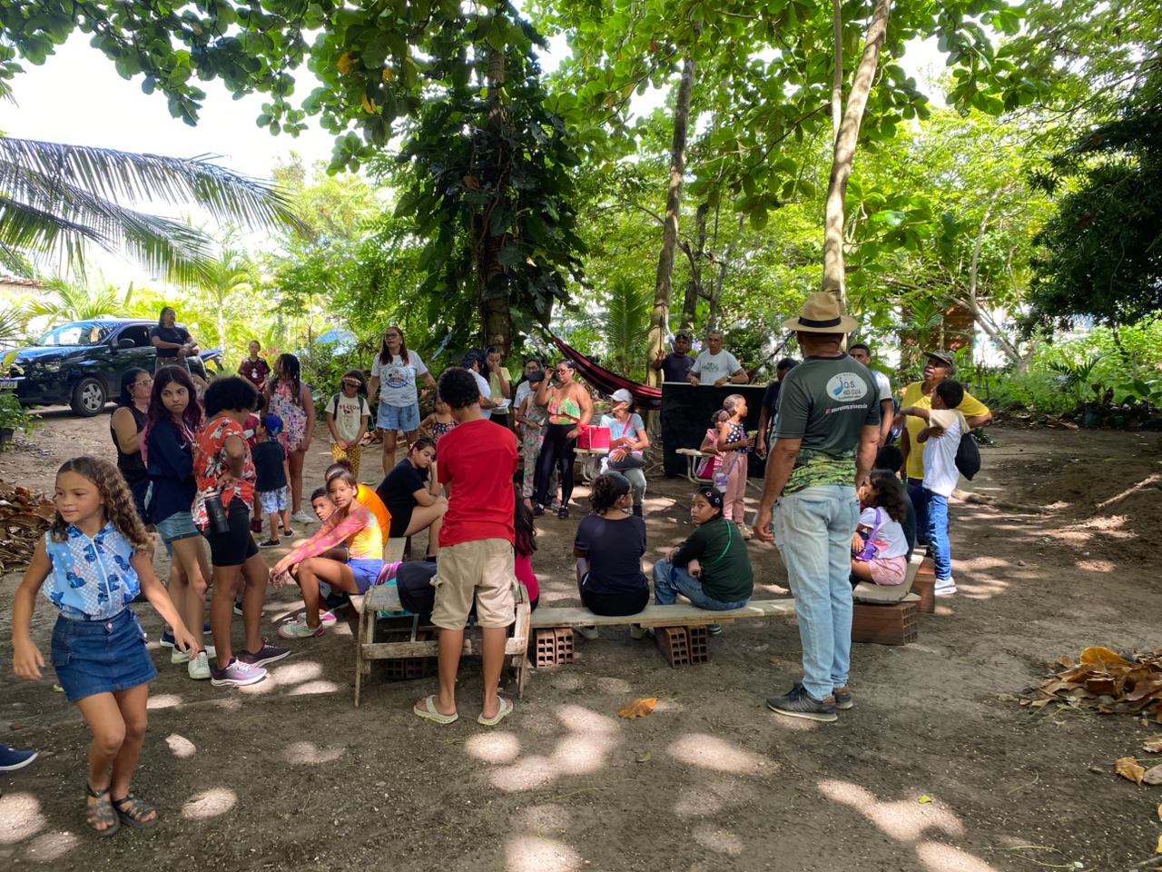 Participantes reunidos ao ar livre entre árvores